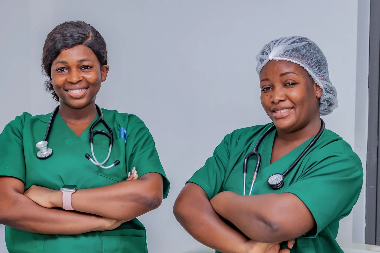 Two nurses in green scrubs smiling in their clinic